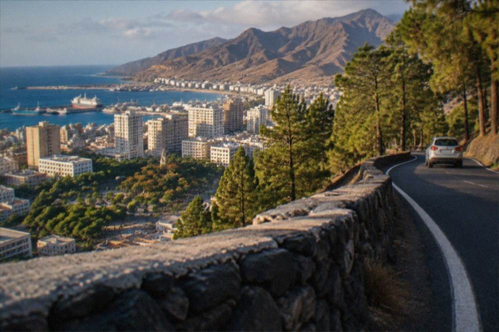 A winding mountain road climbing through pine forest toward volcanic slopes on Tenerife