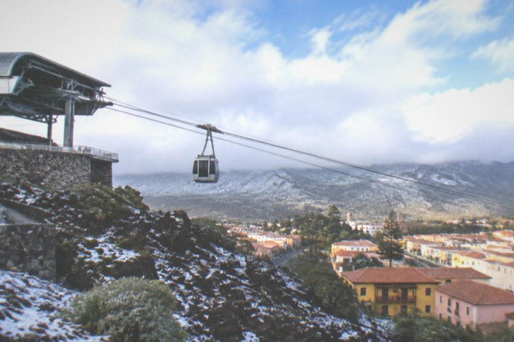 The upper cable car station at La Rambleta under low cloud with a light dusting of snow on dark volcanic rock