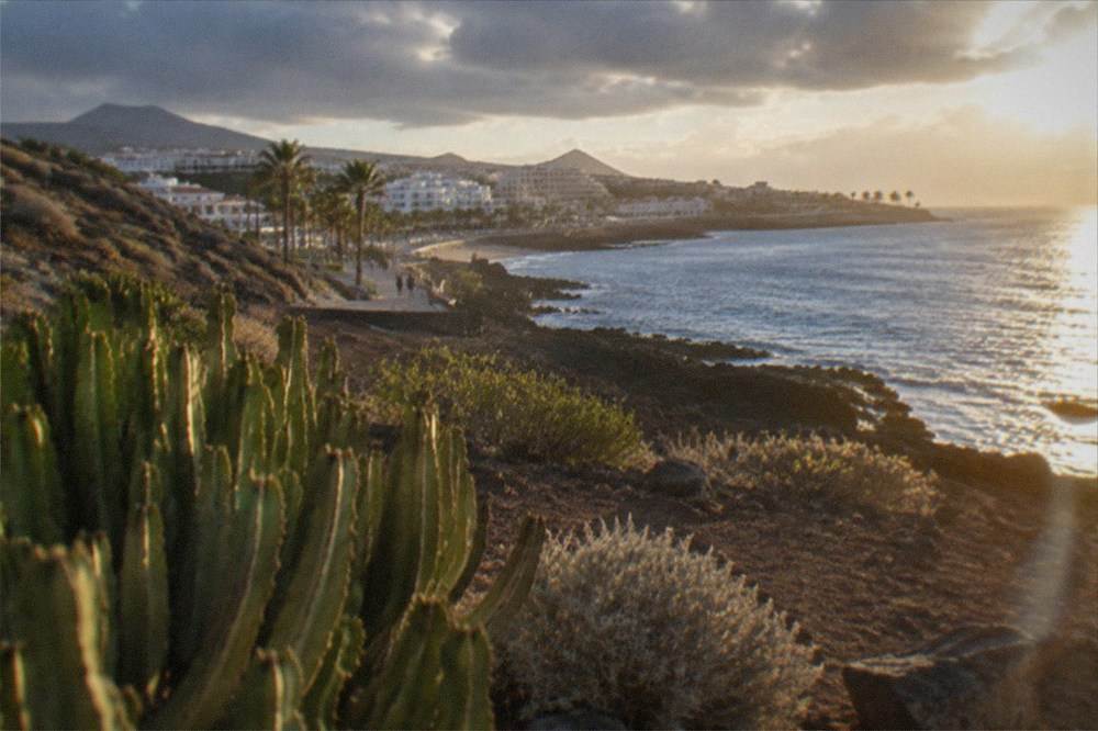 Sunlight breaking through rain clouds over the ocean along the Costa Adeje resort coastline
