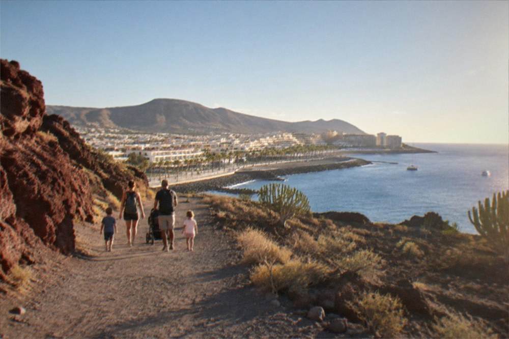 A family with young children walking a wide volcanic path beside reddish rock formations
