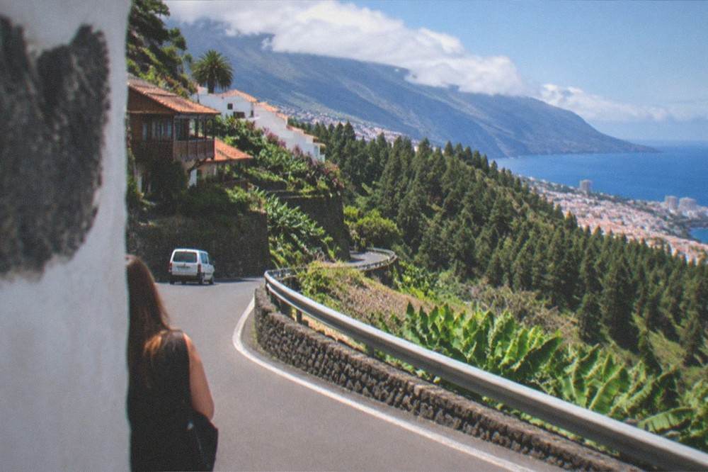 A winding mountain road above pine forest with the ocean in the distance