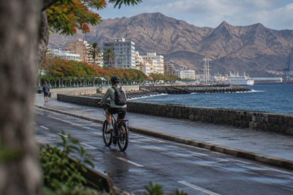 A cyclist riding an e-bike along a coastal road with the Atlantic Ocean on one side