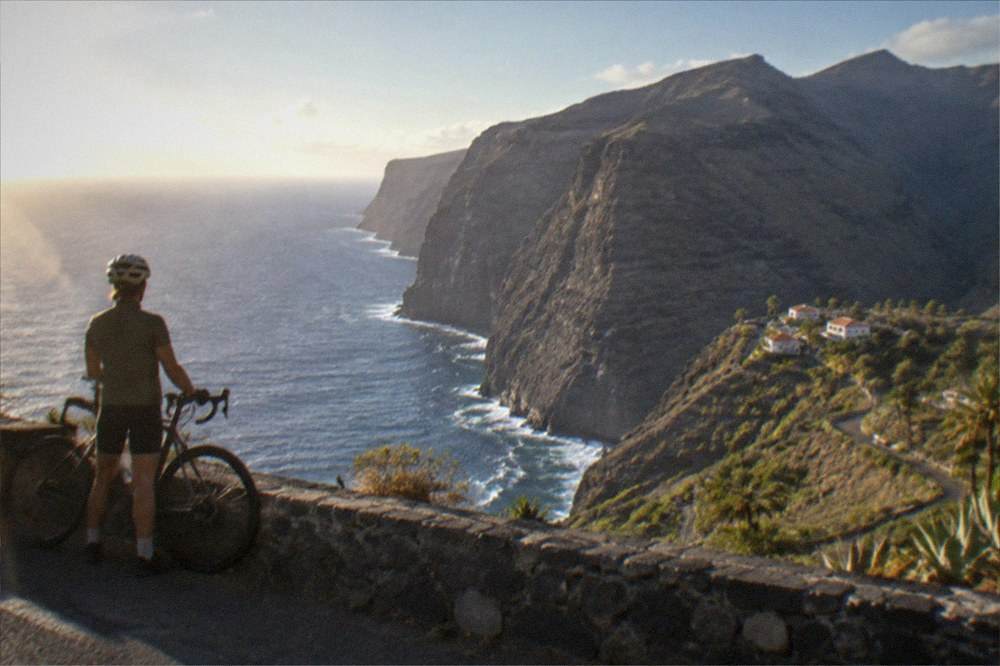 A cyclist looking out over the Los Gigantes cliffs from a roadside viewpoint
