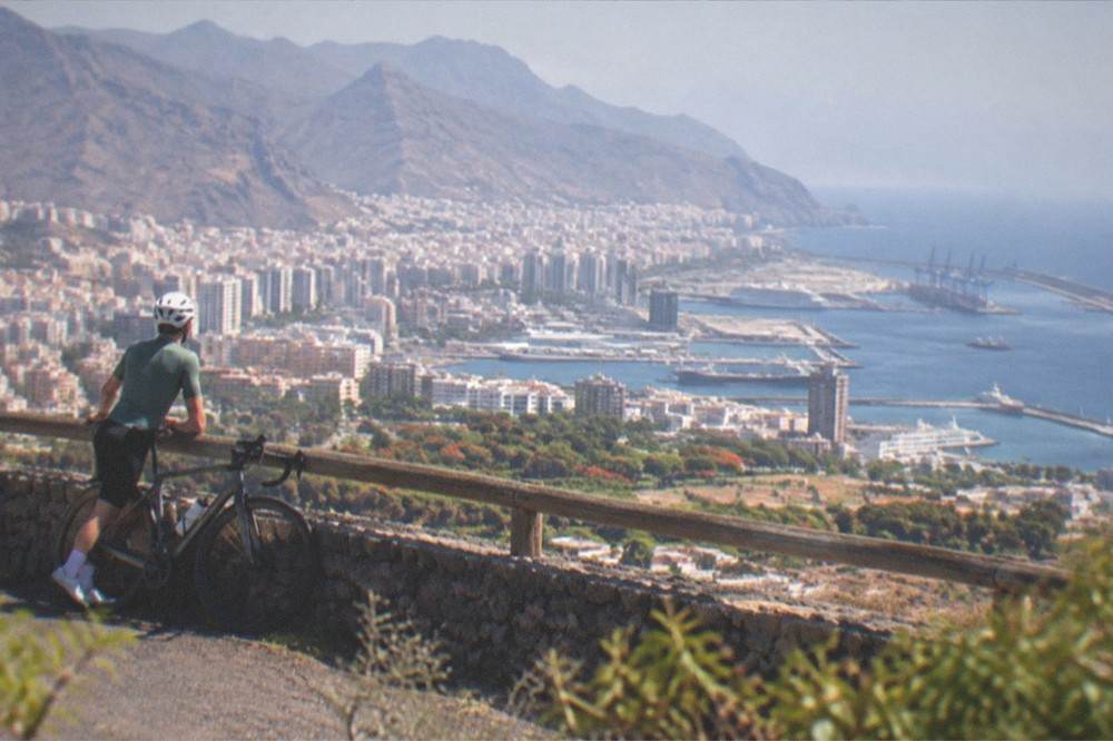 A road cyclist resting at a viewpoint above the south coast of Tenerife