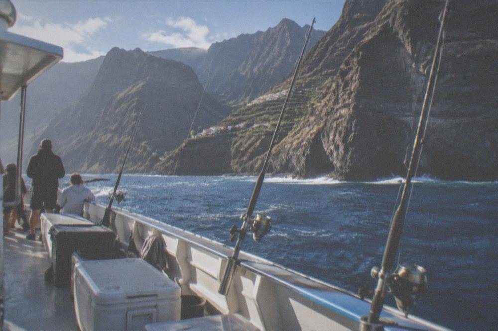 The deck of a charter boat with tackle boxes, rods and a cooler in morning light