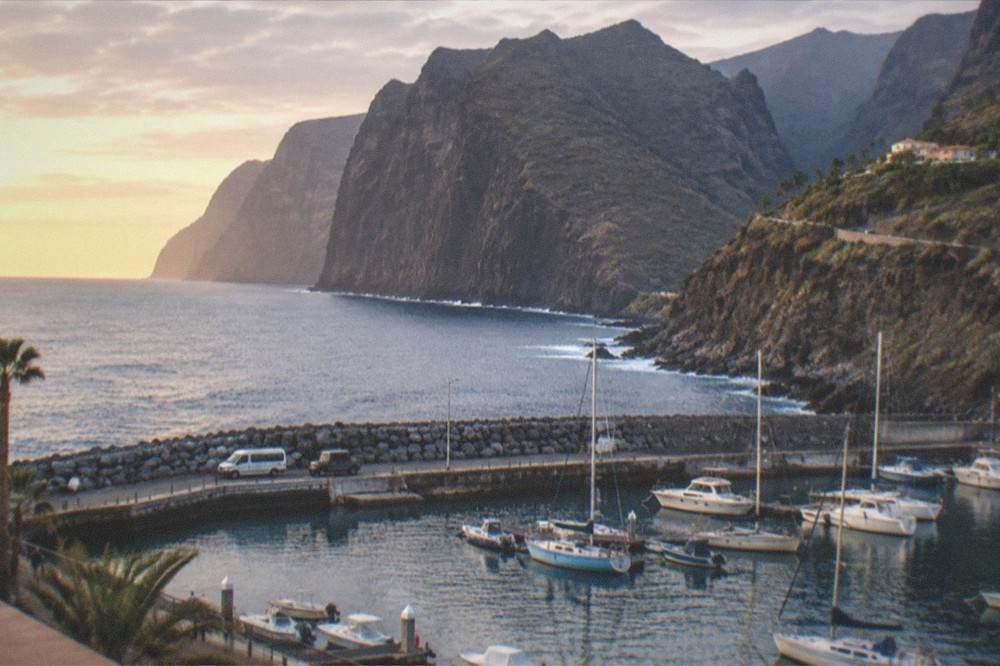 A harbour at golden hour with small boats moored and a calm sea beyond the breakwater