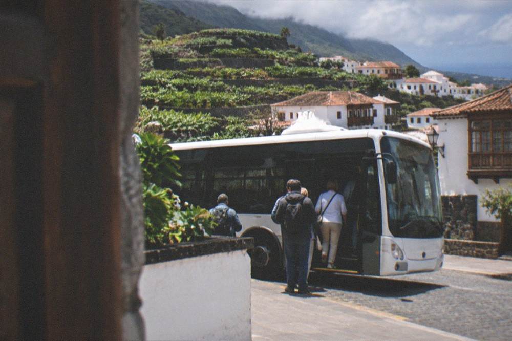 An island bus at a stop in a Tenerife town with passengers boarding