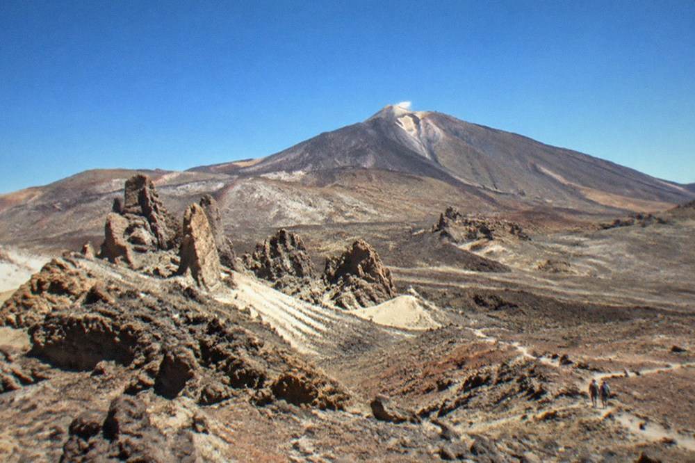 A marked trail sign beside a volcanic rock slope high on Mount Teide