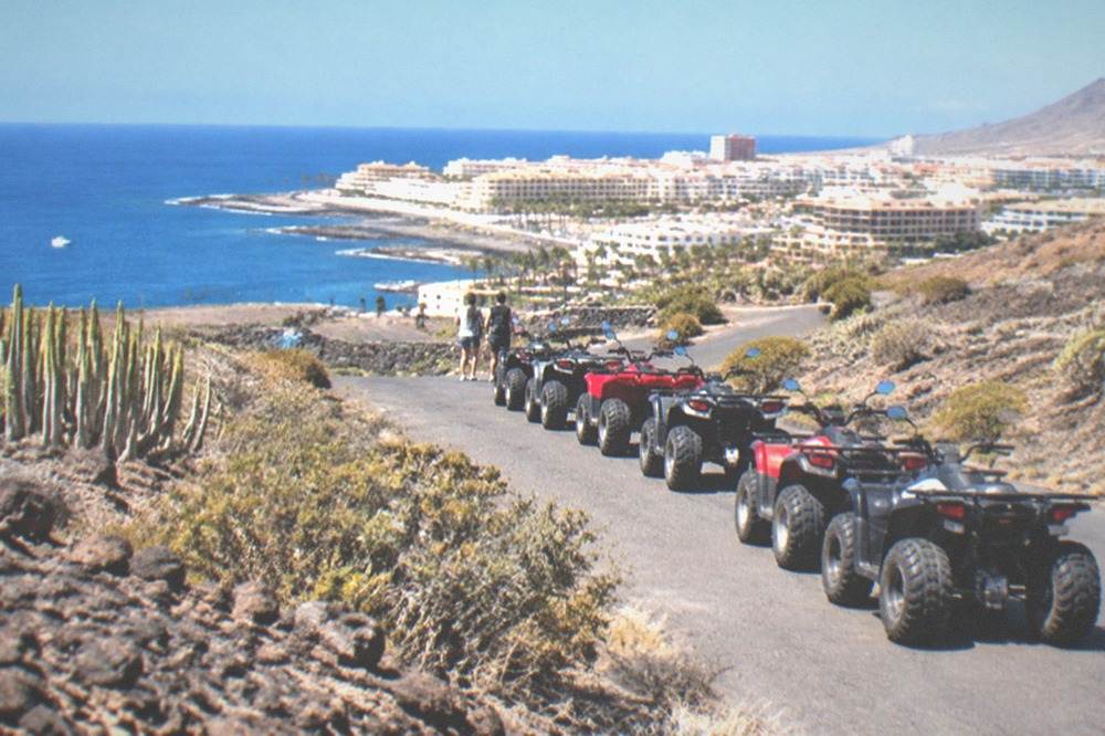 A line of quad bikes parked on a road through dark volcanic terrain