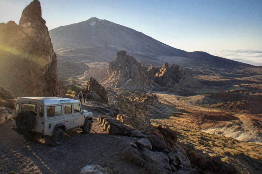 Safari jeep parked beside the Roques de Garcia rock formation under Mount Teide