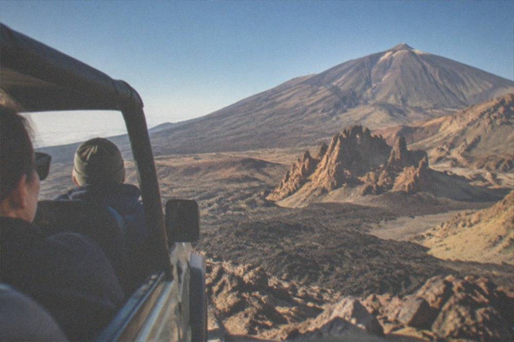 Visitors in a jeep looking out over volcanic slopes inside Teide National Park