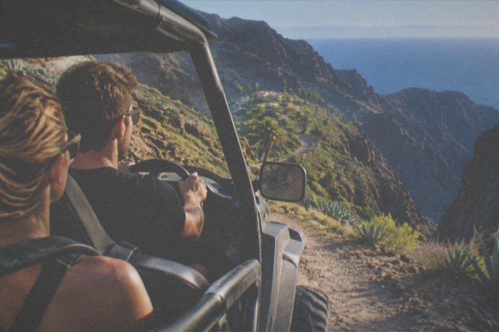 Driver and passenger in an open buggy on a dusty volcanic track in south Tenerife