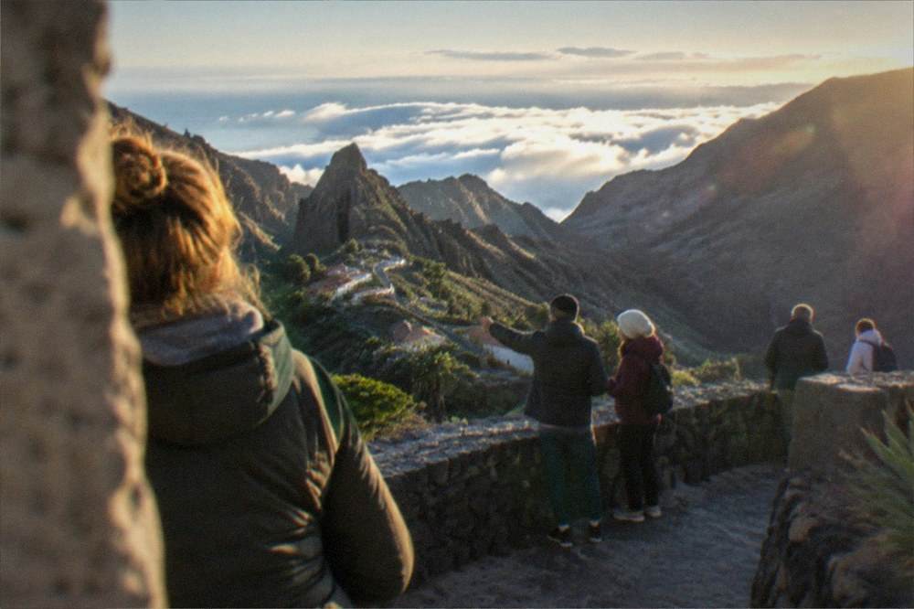 Warmly dressed visitors wrapped in jackets at a high mountain viewpoint above a sea of clouds