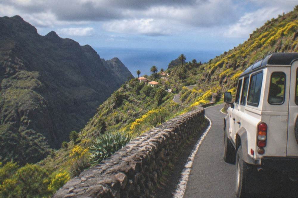 Jeep on an empty mountain road in spring with yellow broom flowers on the volcanic slopes