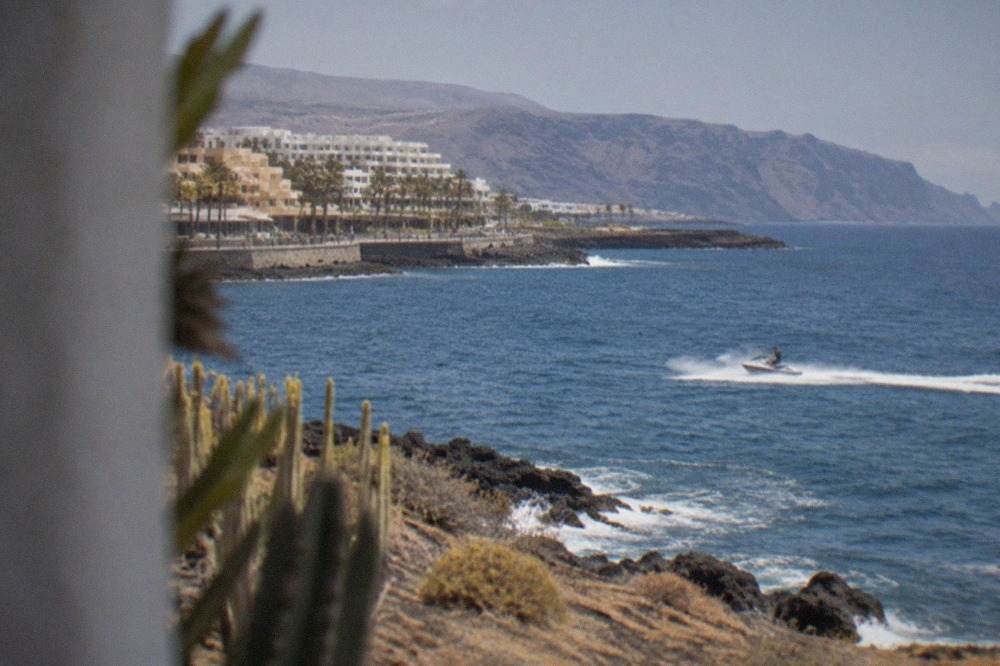 A jet ski cutting across open blue water off the Tenerife coast with distant cliffs on the horizon