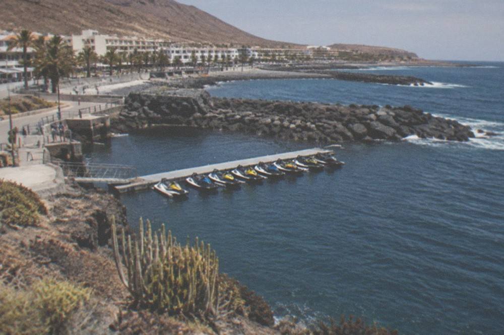 A line of jet skis moored at a pontoon in a small Tenerife harbour at the end of the day