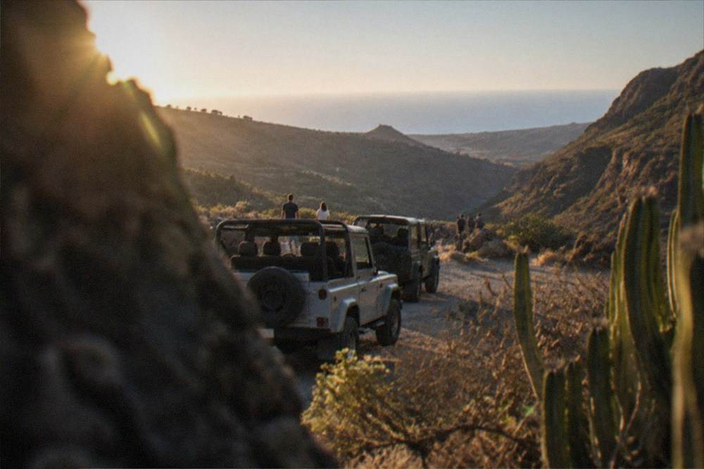 A convoy of jeeps parked on a viewpoint overlooking a deep green valley