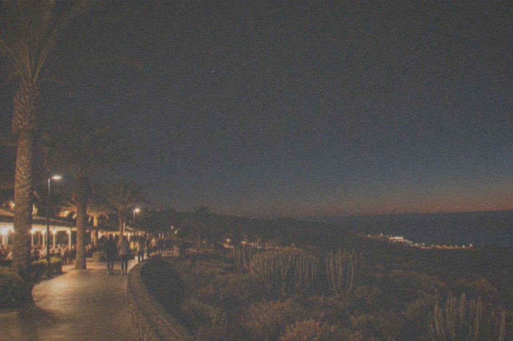 An evening promenade in a Tenerife resort with palm trees and lit restaurants