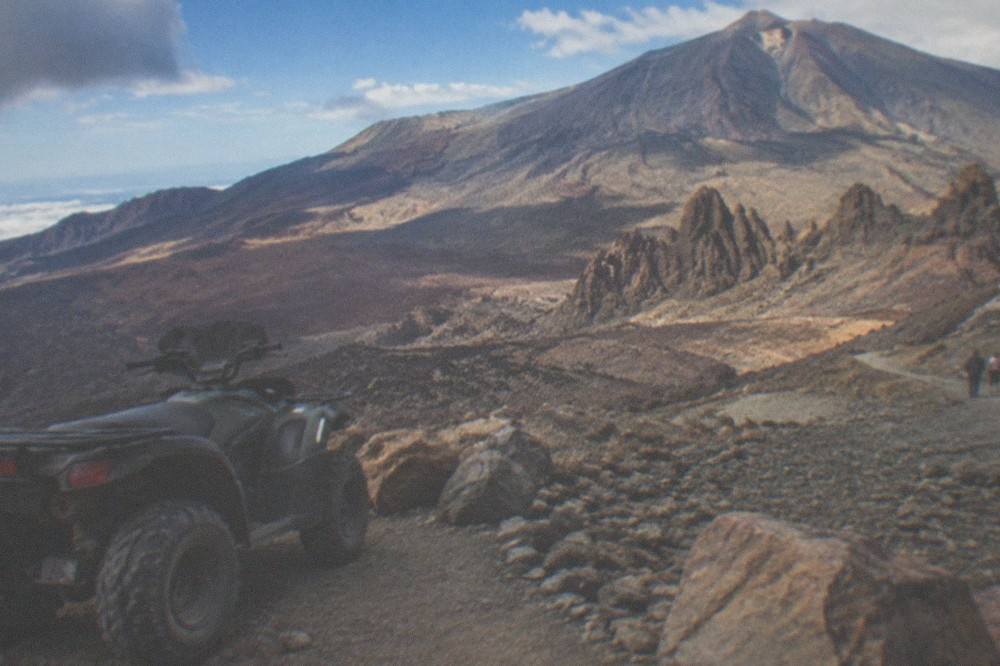 A parked quad bike at a trailhead sign in Teide National Park under a clear sky