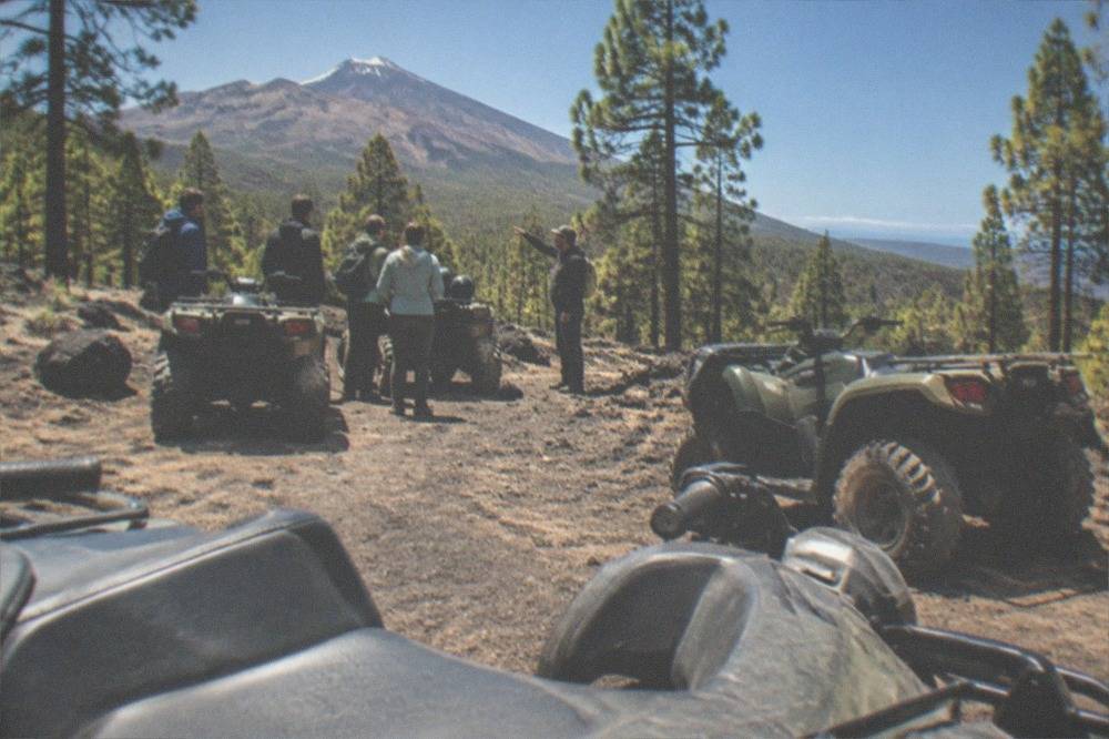 A guide briefing a small group of riders beside their parked quad bikes