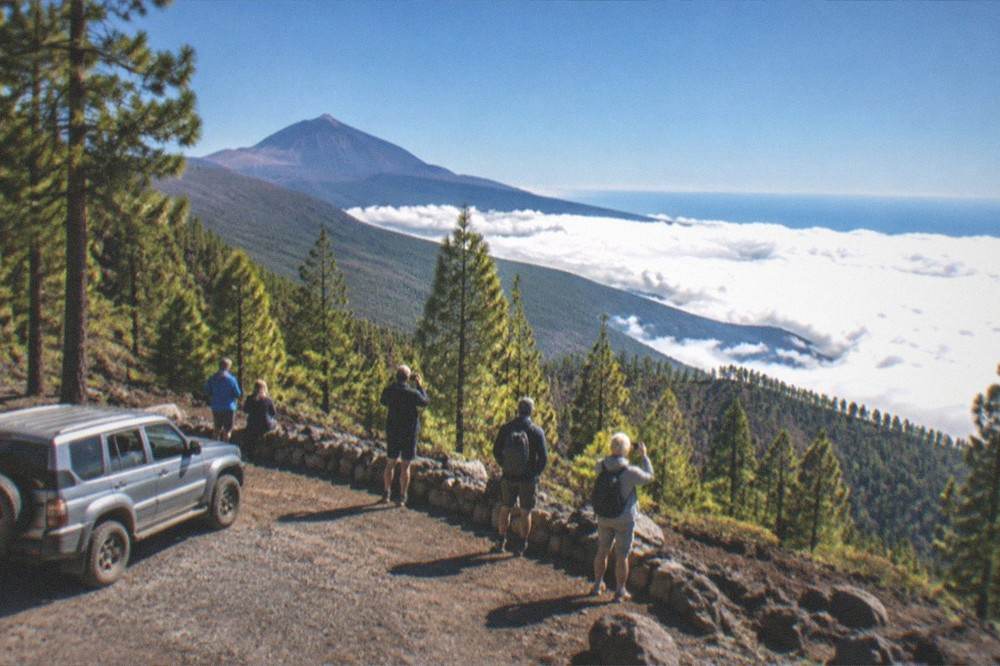 A group of riders taking photos at a viewpoint above a sea of clouds