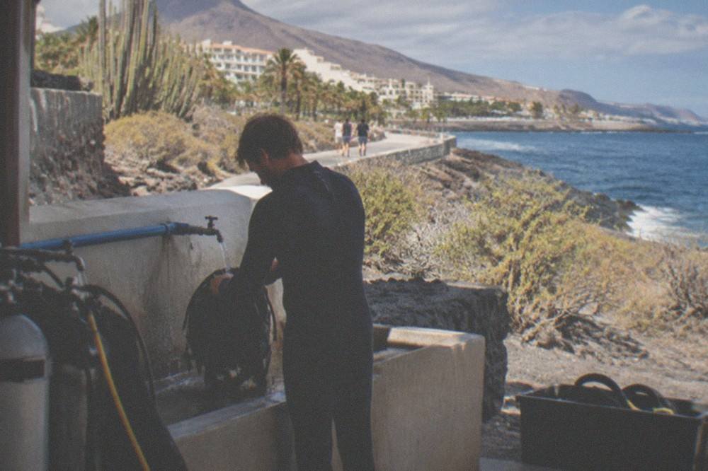 A diver rinsing equipment with a tap at a seafront dive centre