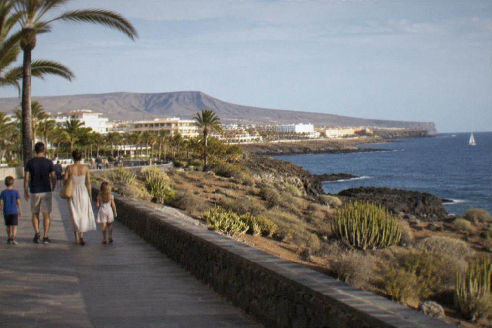 A family walking along a seafront promenade in the evening sunshine