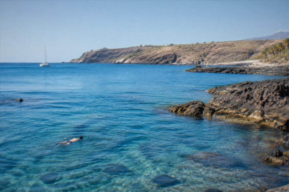 Sunlight passing through clear blue water above a volcanic seabed