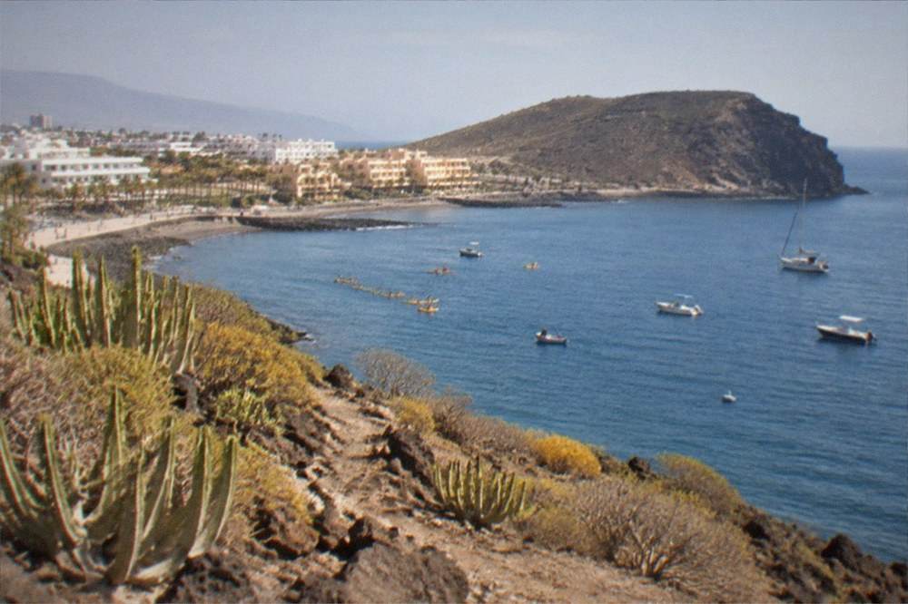 Kayaks and small boats on calm water near a volcanic headland