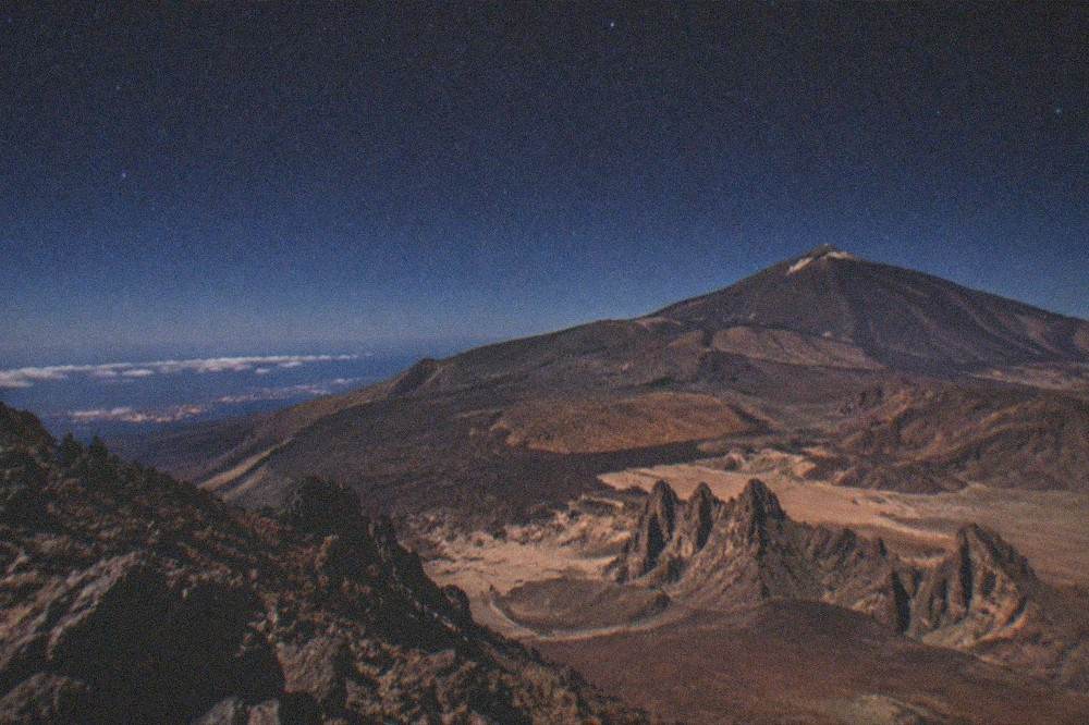 A high mountain viewpoint at night with the distant lights of the towns far below