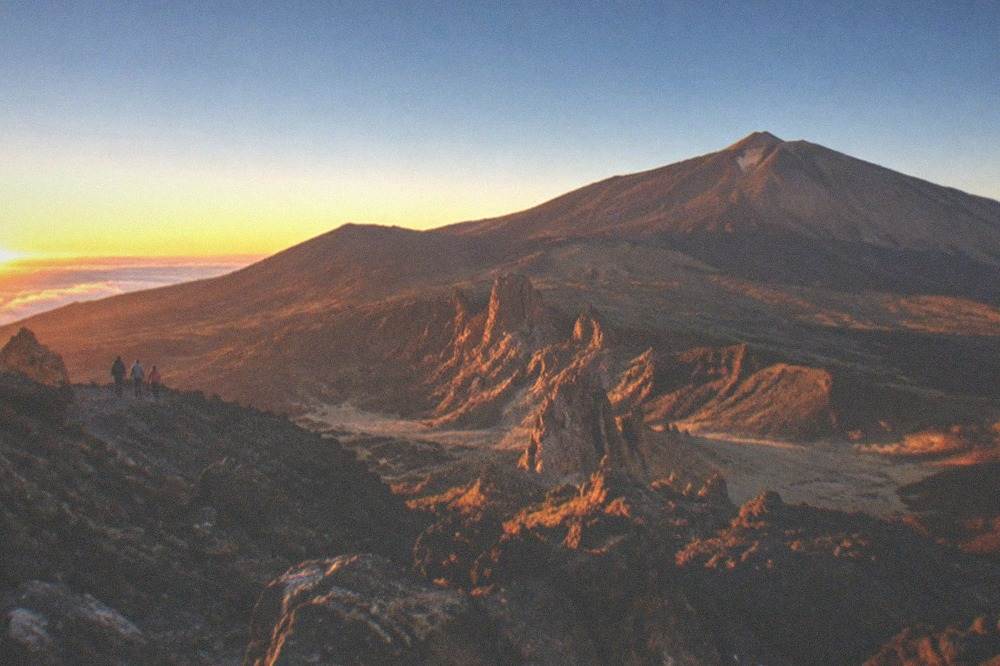 Sunset light over dark volcanic rock with a long shadow across the high ground
