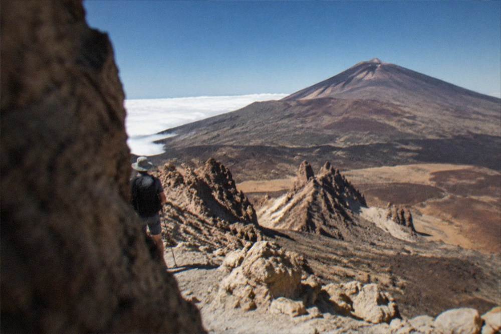 A sea of clouds lying below a sunlit volcanic ridge at high altitude