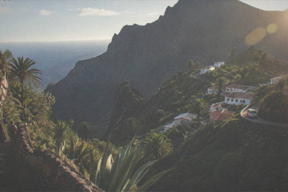 A narrow rocky ravine with a village of small white houses perched on green slopes
