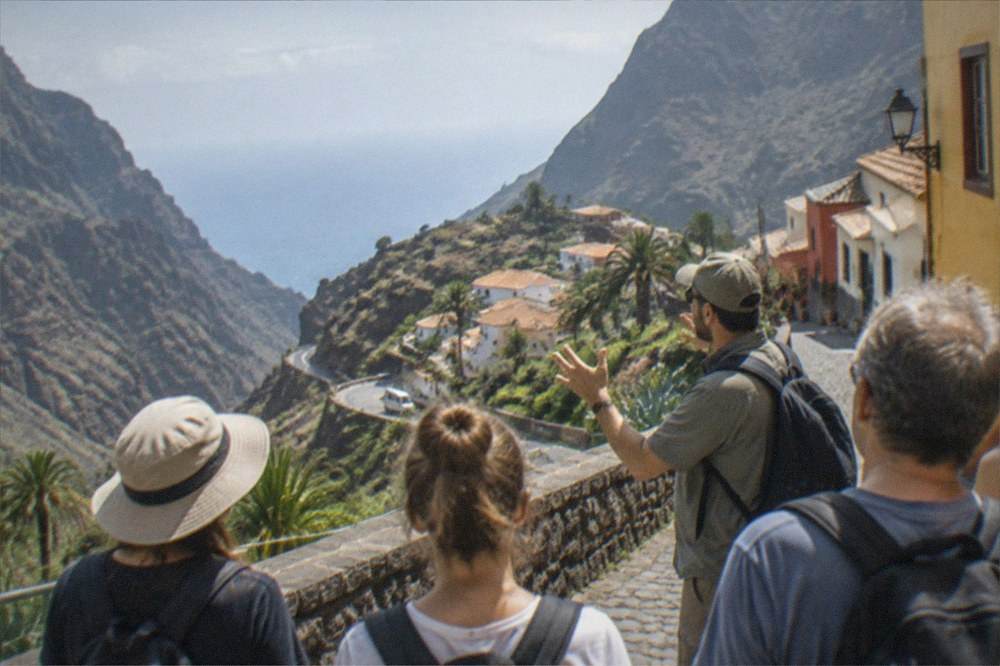 A guide speaking to a small group of tourists on a sunny colonial street with colourful buildings