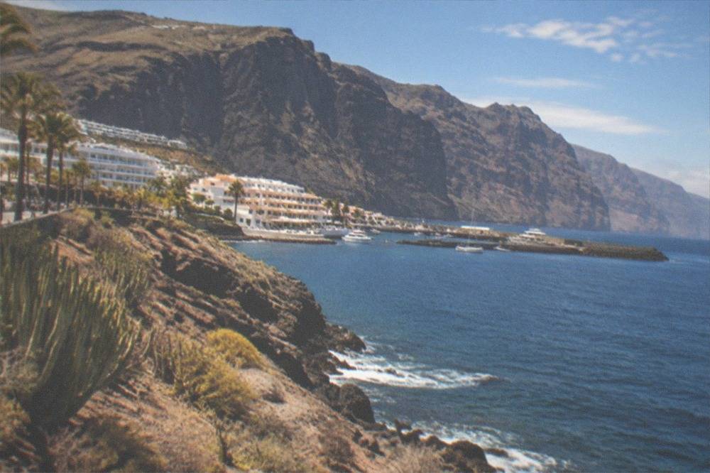 Tall dark sea cliffs above a small harbour town on Tenerife's west coast