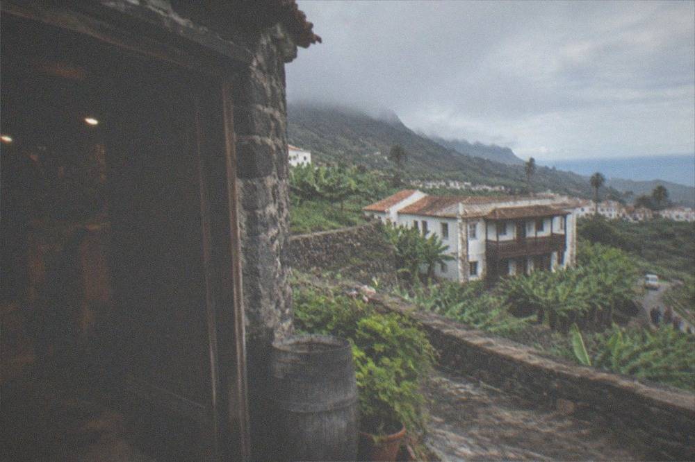 A stone winery building with wooden barrels in a dim cellar